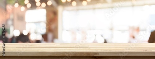 Wood table top on blur restaurant or cafe interior banner background