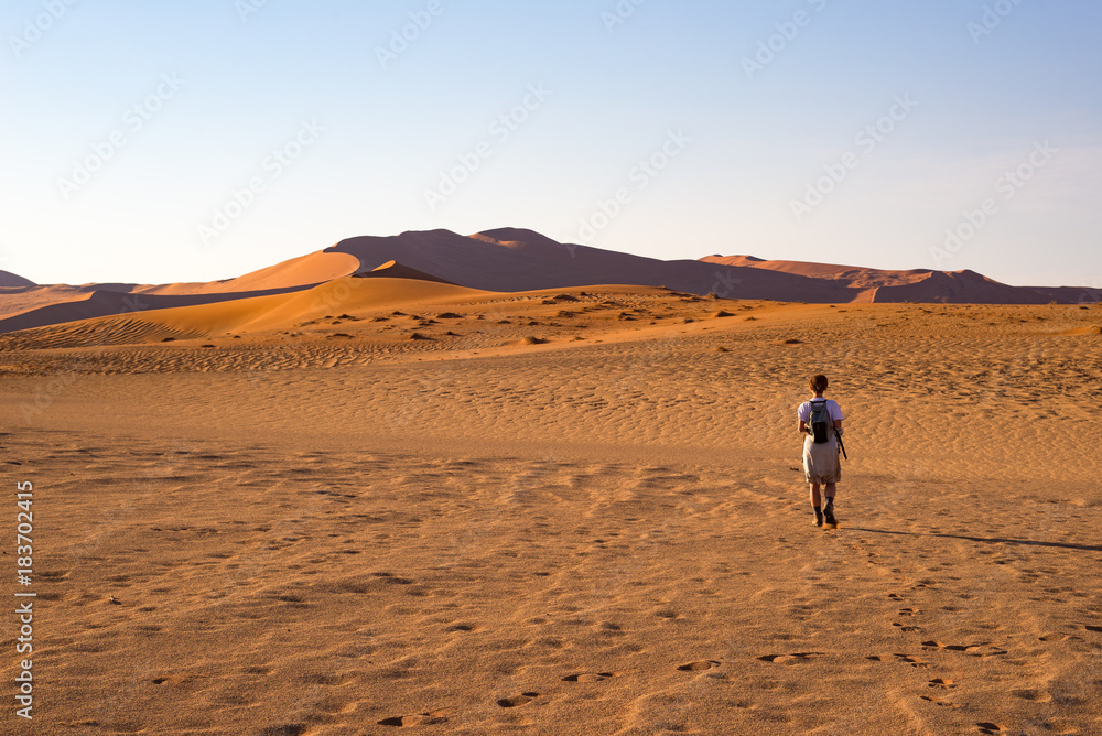 Tourist walking on the scenic dunes of Sossusvlei, Namib desert, Namib Naukluft National Park, Namibia. Adventure and exploration in Africa. Tourist walking on the scenic dunes of Sossusvlei, Namib desert, Namib Naukluft National Park, Namibia. Adventure and exploration in Africa.