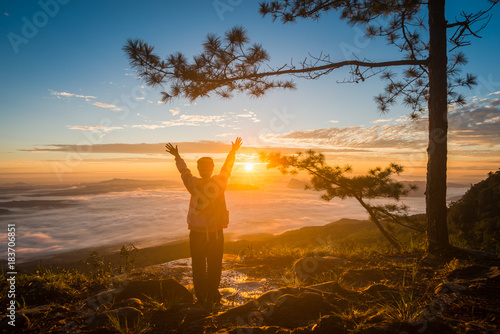 Young woman watching the sun rise from top of mountain