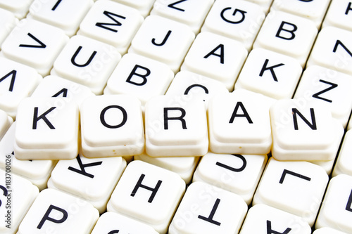 Koran text word crossword. Alphabet letter blocks game texture background. White alphabetical cubes blocks letters on crossword letters educational toy background. Koran title. photo