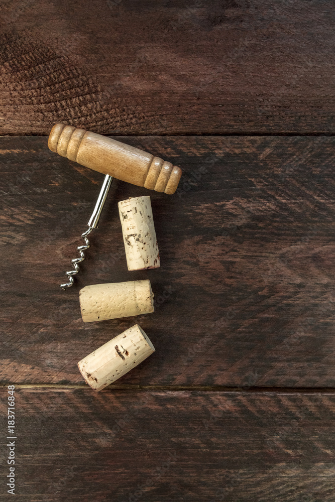 Photo of wine corkscrew and corks on dark background