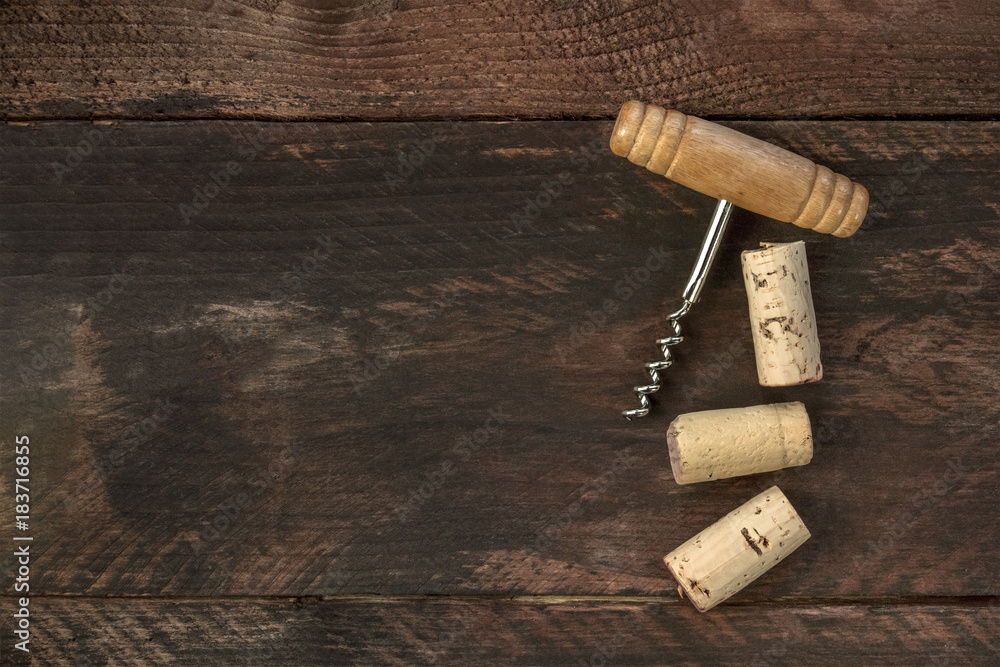 Photo of wine corkscrew and corks on dark background