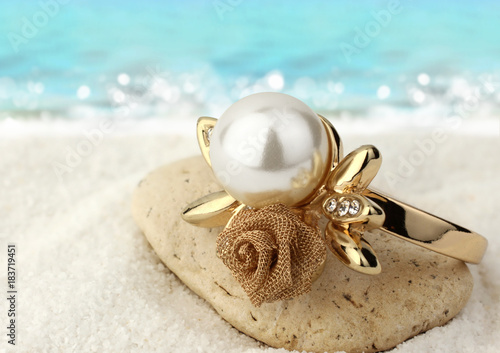 Macro of Jewelery ring with pearl on sand beach