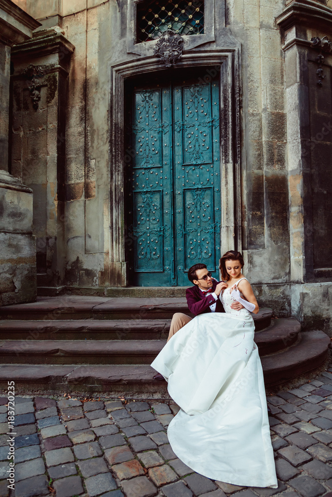 Happy young couple sitting on the stairs of an ancient church