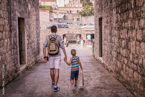 Father and son walking through the city and holding hands.