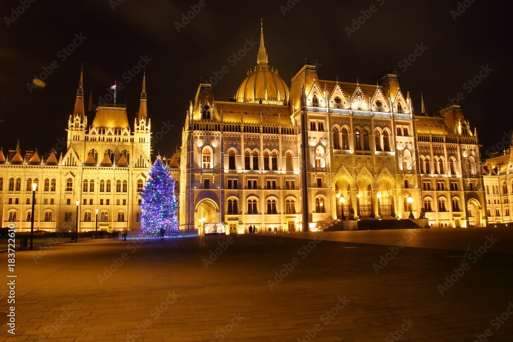 Budynek węgierskiego parlamentu w Budapeszcie, w nocy, podświetlony, choinka bożonarodzeniowa przed budynkiem