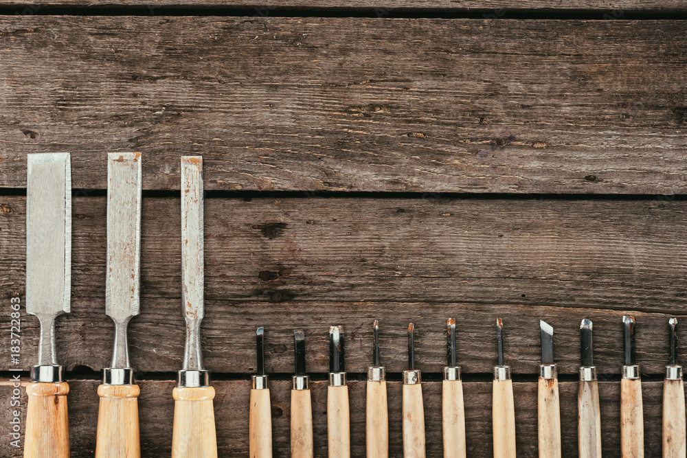 flat lay with wooden chisels for woodcraft on dark wooden tabletop flat lay with wooden chisels for woodcraft on dark wooden tabletop