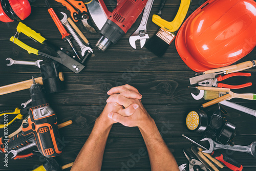 partial view of hands in lock and carpentry equipment around on wooden surface photo