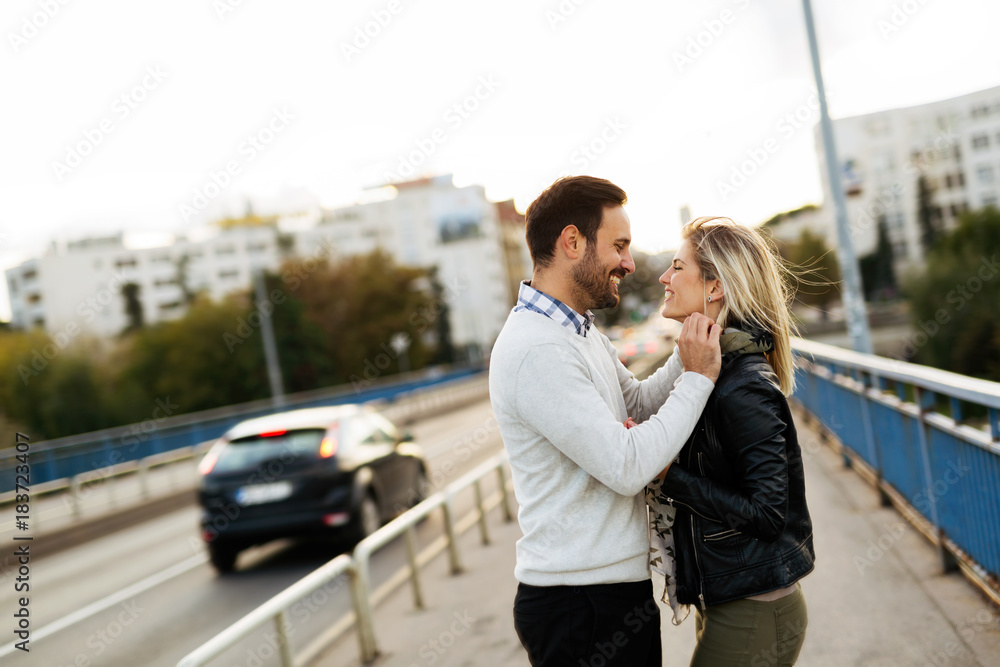 Happy young couple hugging and kissing on bridge