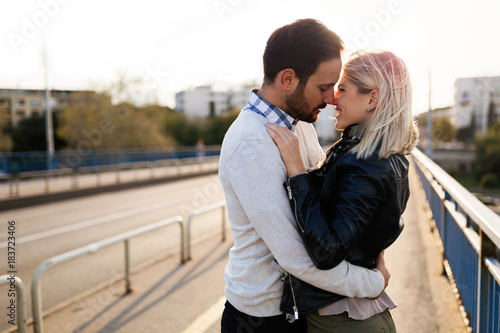 Happy young couple hugging and kissing on bridge