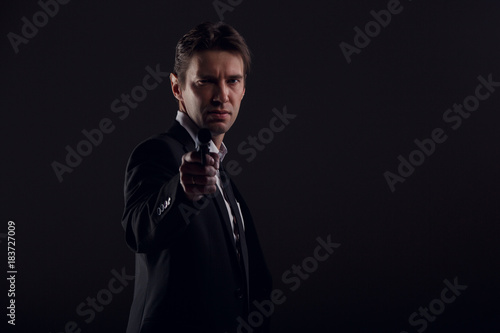 Image of male bodyguard with gun isolated on black background. © Sergey