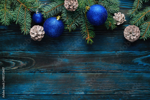 New Year and Christmas decorations Pine tree branches, cones, blue Christmas toys on a wooden background.