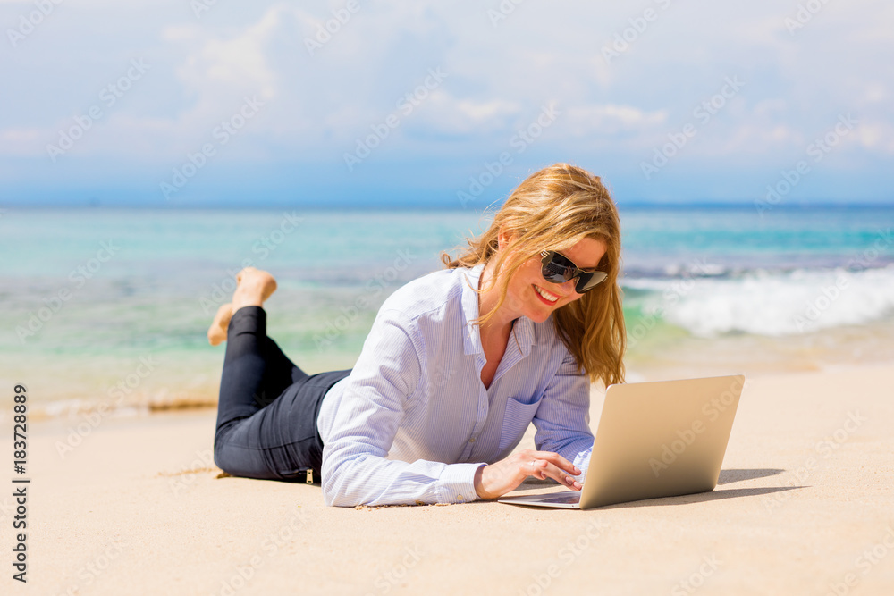 Business woman working with laptop on the beach