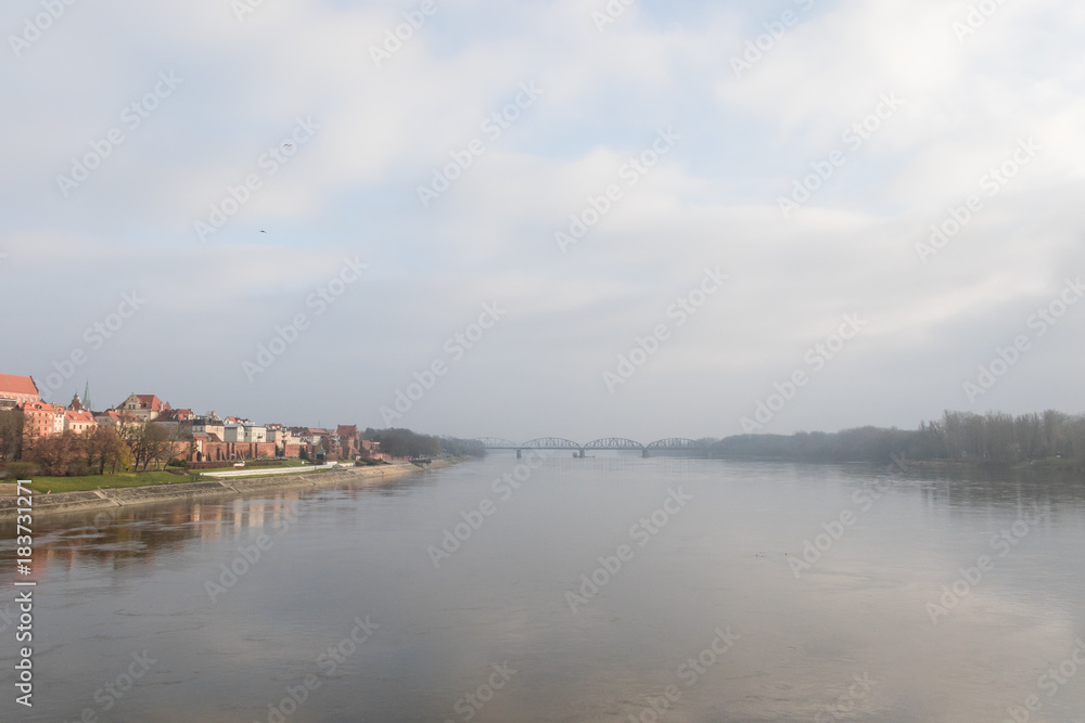 Foggy panorama with the bridge across the Vistula and two shores of the river. Beautiful medieval town of Torun in Poland listed on the UNESCO World Heritage List.