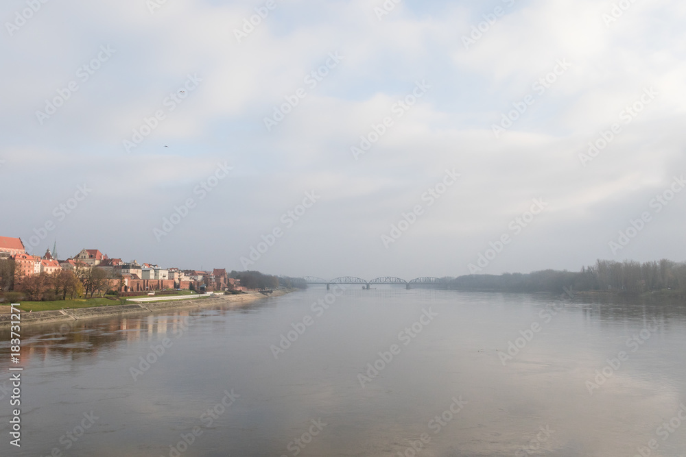Foggy panorama with the bridge across the Vistula and two shores of the river. Beautiful medieval town of Torun in Poland listed on the UNESCO World Heritage List. Foggy panorama with the bridge across the Vistula and two shores of the river. Beautiful medieval town of Torun in Poland listed on the UNESCO World Heritage List.