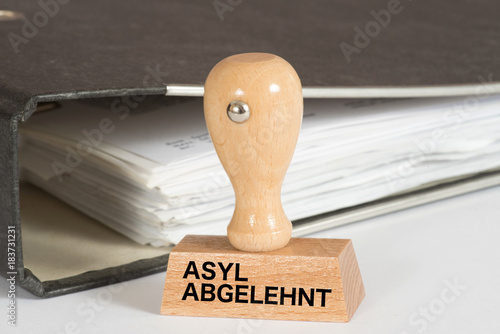 Ein Ordner mit Unterlagen und ein Stempel mit dem Aufdruck Asyl Abgelehnt