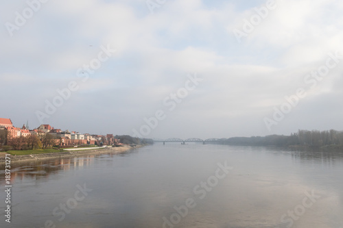 Fototapeta Naklejka Na Ścianę i Meble -  Foggy panorama with the bridge across the Vistula and two shores of the river. Beautiful medieval town of Torun in Poland listed on the UNESCO World Heritage List.