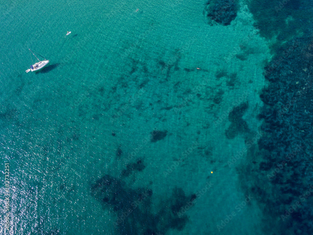 Vista aerea di una barca ormeggiata che galleggia su un mare trasparente. Immersioni relax e vacanze estive. Coste e fondale marino Vista aerea di una barca ormeggiata che galleggia su un mare trasparente. Immersioni relax e vacanze estive. Coste e fondale marino