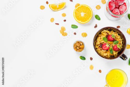 Cereal, morning breakfast, corn flakes, raisins, almonds, mint leaves, orange juice, strawberry, top view, white background, flat lay. The concept of healthy, proper nutrition, ditox.