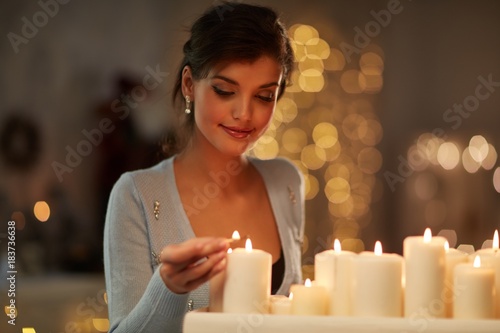 Woman with candles, fireplace, christmas lights.