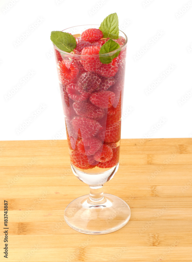 Glass of water full with raspberries isolated on wooden plank Glass of water full with raspberries isolated on wooden plank