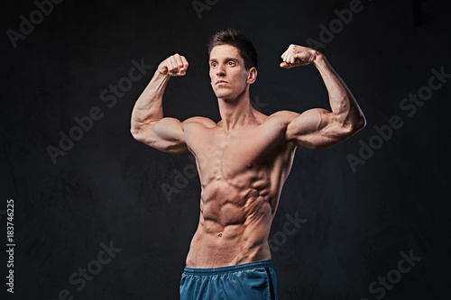 Shirtless muscular male over dark background.