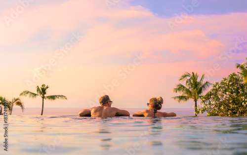 Romantic couple looking at beautiful sunset in luxury infinity pool