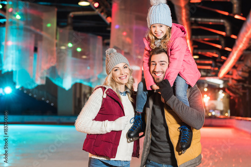 happy young family smiling at camera while spending time together on rink