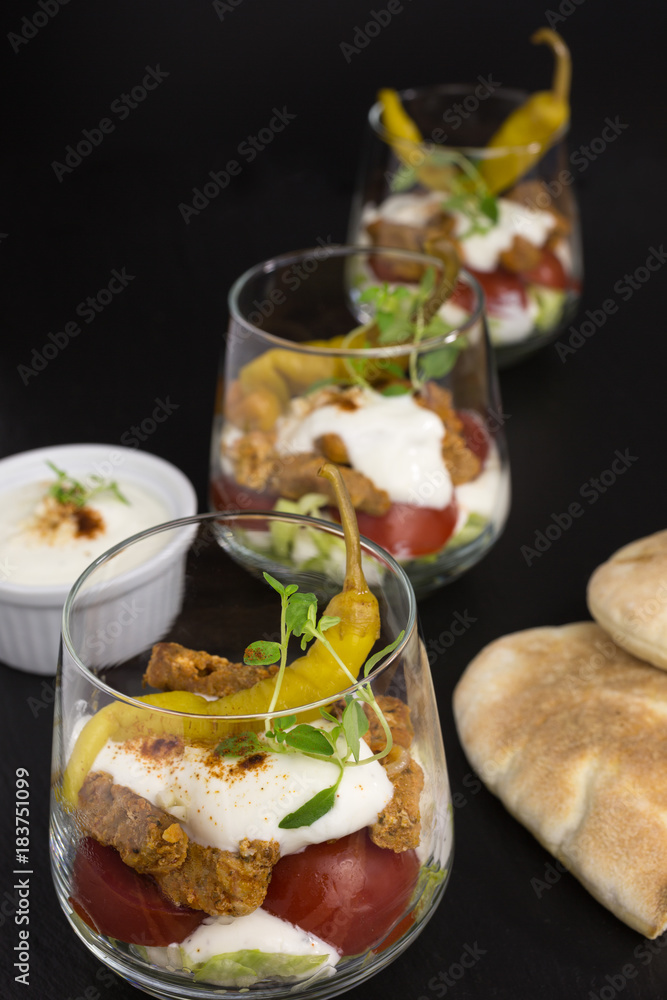 portion of gyros in a glass with lettuce, tomato and meat covered with tzatziki portion of gyros in a glass with lettuce, tomato and meat covered with tzatziki