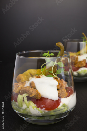 portion of gyros in a glass with lettuce, tomato and  meat covered with tzatziki