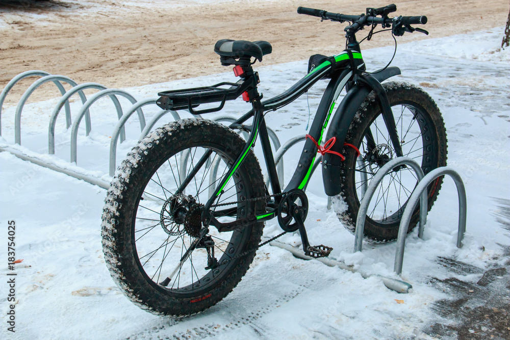 Bicycle with a wide rubber in the parking lot near the store in the city in the winter