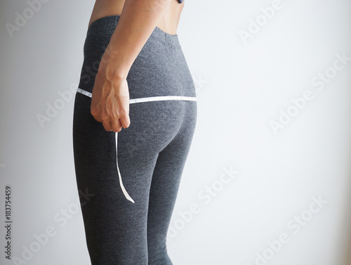 Slim body of asian woman with a measuring tape on white background.