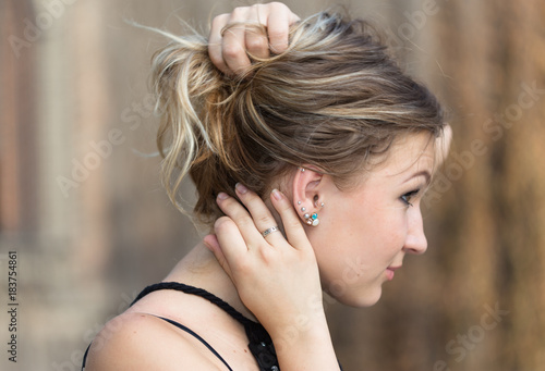 Side view of girl holding her hair in arms to show her earrings