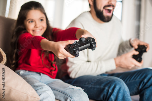 cropped image of father and daughter playing video game with game pads