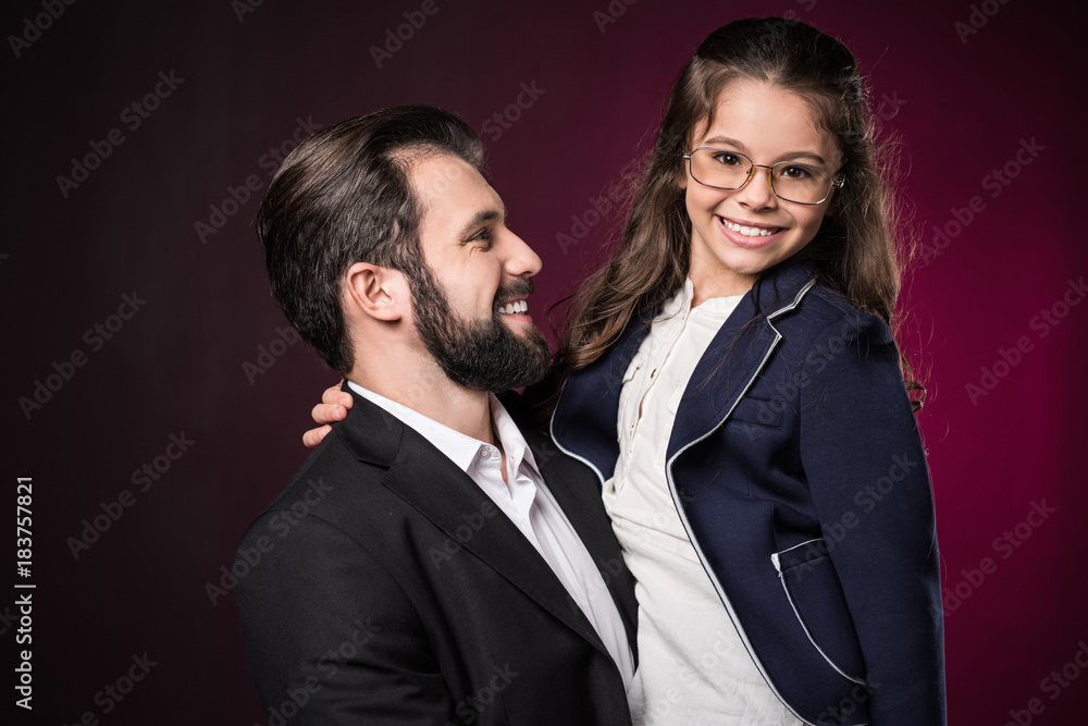 smiling father holding daughter on burgundy smiling father holding daughter on burgundy