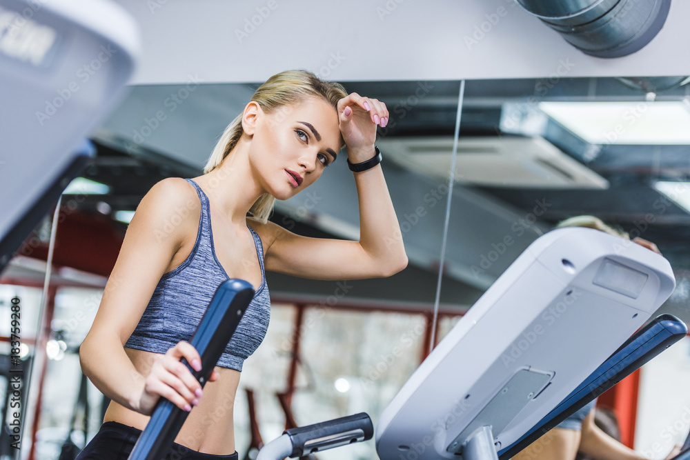 exhausted sportive woman working out on elliptical machine at gym exhausted sportive woman working out on elliptical machine at gym