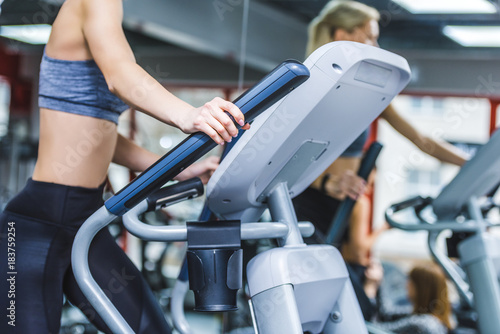 cropped shot of sportive woman working out on elliptical machine at gym