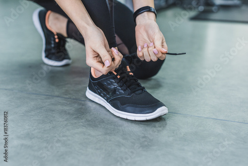 cropped shot of woman lacing up sneakers before training