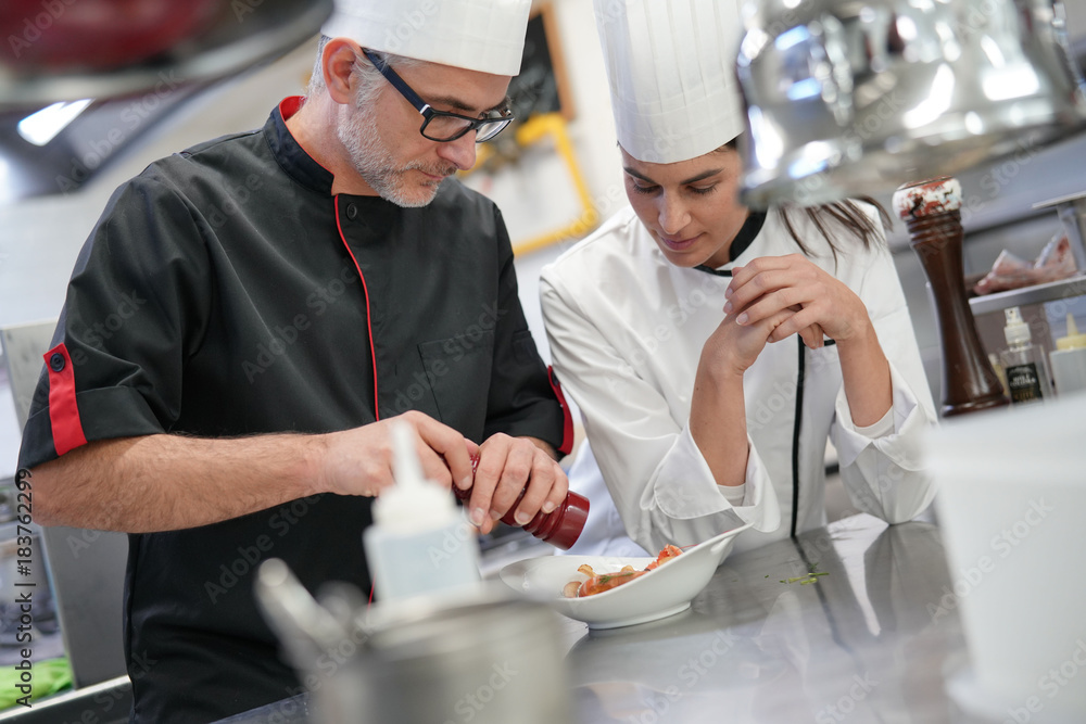Professional cook chefs in kitchen improving dish composition Professional cook chefs in kitchen improving dish composition