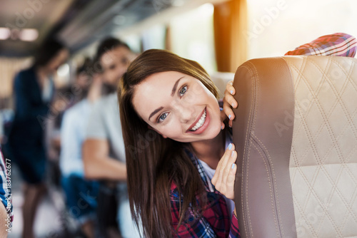 Woman posing on bus. She sits and smiles. Around her sit the other passengers.
