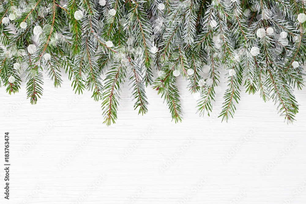 Fototapeta premium Christmas background. Christmas fir tree branches with snow on white wooden background. Copy space, top view