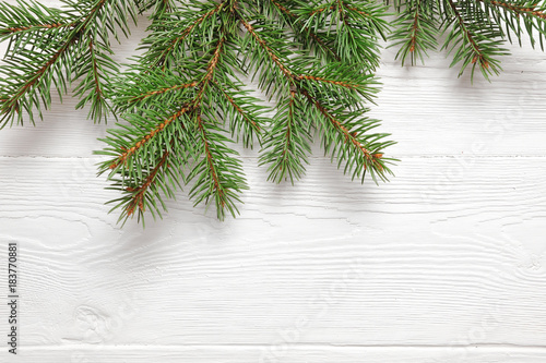 Mockup Christmas tree branches border over white wooden background, with space for your text