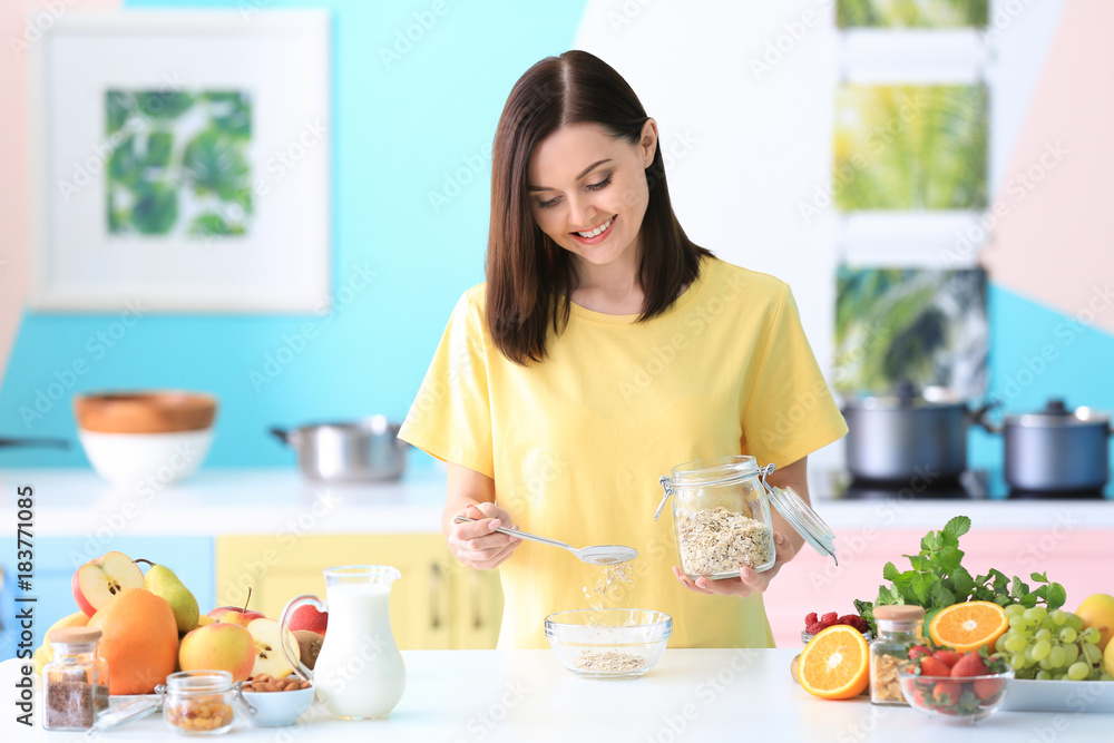 Young woman preparing oatmeal porridge on table in kitchen