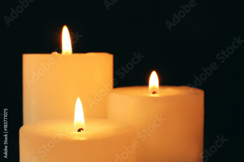 Wax candles burning in darkness, closeup