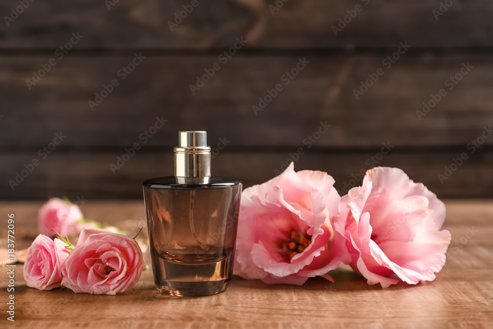 Bottle of perfume with flowers on wooden table Bottle of perfume with flowers on wooden table