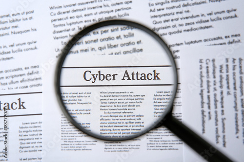 Headline "Cyber attack" in newspaper under magnifying glass, closeup