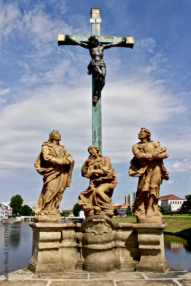 Statue of a crucified Jesus / Sculptures on a stone bridge of czech town Pisek