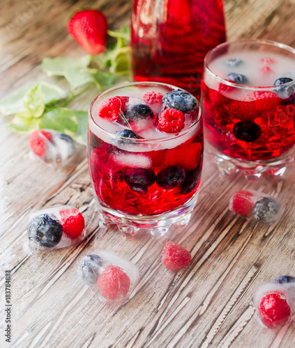 Summer berry lemonade with frozen berries on a wooden rustic table, selective focus