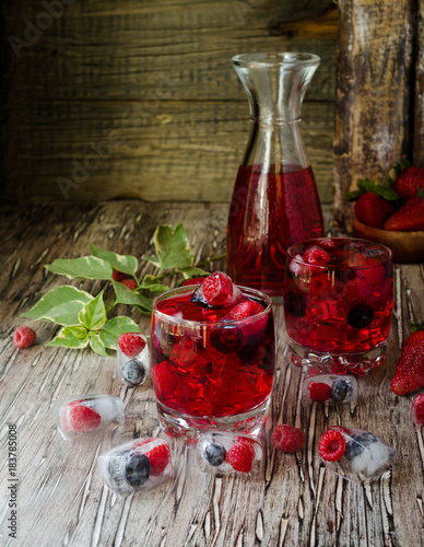 Summer berry lemonade with frozen berries on a wooden rustic table, selective focus photo