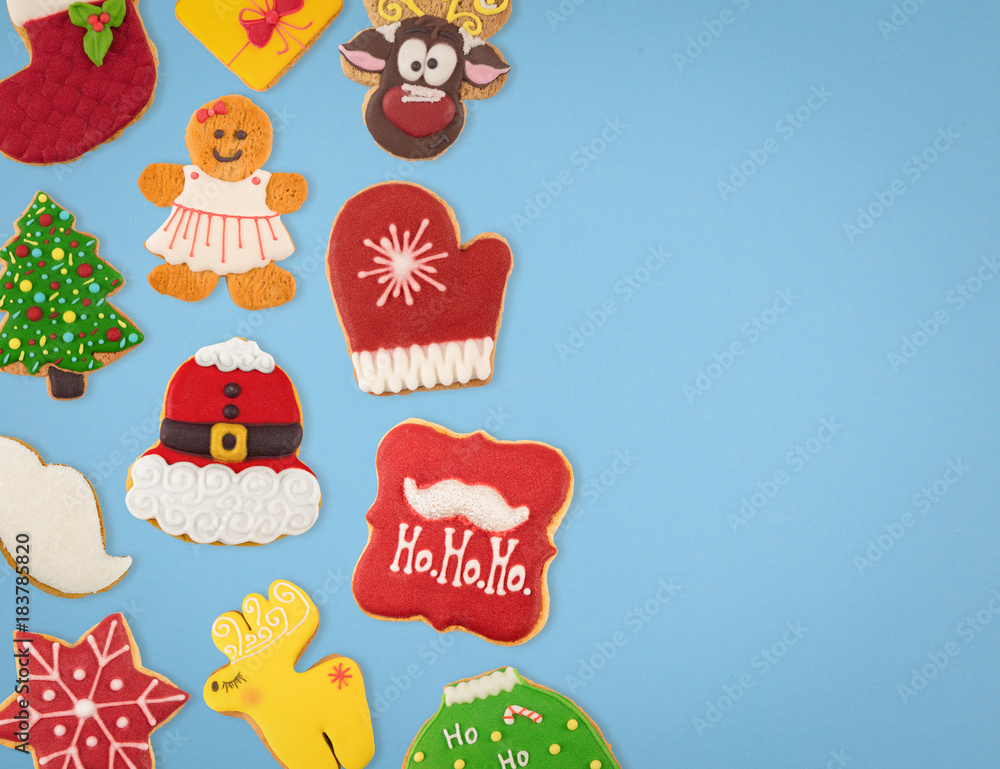Christmas cookies of different shapes and sizes with a festive decor on a blue background. Holiday Poster concept.